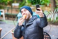 Man eating a croissant and taking a selfie in a garden Royalty Free Stock Photo