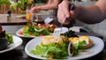 Man eating full meal as poached egg, salad and avocado toast in cafe. Close-up of man with fork pierces poached egg and Royalty Free Stock Photo