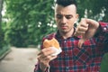 Man opening a hamburger. Man is eating in the park Royalty Free Stock Photo