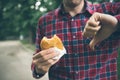 Man opening a hamburger. Man is eating in the park Royalty Free Stock Photo