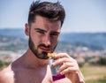 Man eating protein bar outdoor in summer, looking at camera Royalty Free Stock Photo