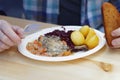 Man eating roasted duck with red cabbage and potato