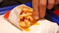 Man eating salted McDonalds fast food restaurant fries and a burger laying on a table, fingers, object closeup, nobody, shallow