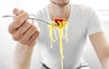 Man eating tasty spaghetti with tomato sauce