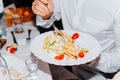 Man eating tomato salad, crackers, greens from a plate indoors, close-up. Festive feast concept. selective focus on food