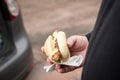 Man eating typical grilled German Bratwurst sausage street food with bread roll bun and mustard on the go