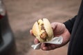 Man eating typical grilled German Bratwurst sausage street food with bread roll bun and mustard on the go