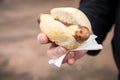 Man eating typical grilled German Bratwurst sausage street food with bread roll bun and mustard on the go