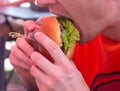 A man eats a big juicy burger. Burger with cheese, vegetables, cutlets close-up Royalty Free Stock Photo