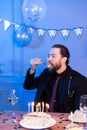 A man eats a cake with his eyes closed at the table. Celebration alone. Royalty Free Stock Photo