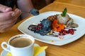 A man eats coal and chicory ice cream, decorated with waffles and fresh berries