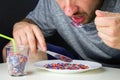 The man eats pieces of crushed recycled plastic from white plate. Royalty Free Stock Photo