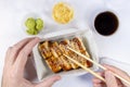 A man eats rolls with chopsticks. Top view. Roll with smoked eel, pickled ginger, soy sauce, sesame. White background