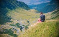 Man on the edge of abyss with picturesque view of Transfagaras mountain road in the Transylvanian Alps, Romania