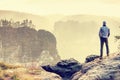 Man on edge of cliff high above misty valley. Travel hiking and Lifestyle. Royalty Free Stock Photo