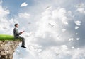 Man on edge reading book and paper planes flying in air Royalty Free Stock Photo