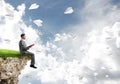 Man on edge reading book and paper planes flying in air Royalty Free Stock Photo