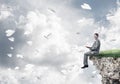 Man on edge reading book and paper planes flying in air Royalty Free Stock Photo
