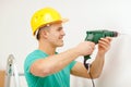 Man with electric drill making hole in wall