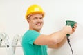 Man with electric drill making hole in wall