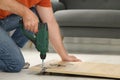 Man with electric screwdriver assembling furniture on floor indoors, closeup. Space for text Royalty Free Stock Photo