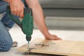 Man with electric screwdriver assembling furniture on floor indoors, closeup Royalty Free Stock Photo