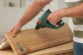 Man with electric screwdriver assembling furniture at table indoors, closeup Royalty Free Stock Photo