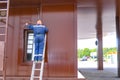 Man electrician master extends an electric wire over the window. Standing on a stepladder