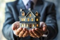 man in an elegant blue suit holds model of an apartment building in his palms,hands in close-up,concept of mortgage lending,real