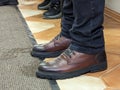 A man in elegant leather shoes leaves wet footprints on the floor indoors. No face