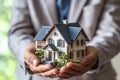 man in an elegant suit holds a model of an apartment building in his palms,hands in close-up,concept of mortgage lending, real