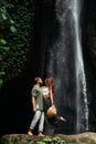 A man embraces a woman at a waterfall. A couple in love at a waterfall. Honeymoon trip. Happy couple in Bali. A beautiful couple