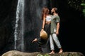 A man embraces a woman at a waterfall. A couple in love at a waterfall. Honeymoon trip. Happy couple in Bali.