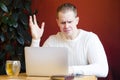 Man emotionally looks at laptop, screen having operational problems, confused biracial male working on computer, angry of slow int