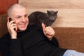 Man emotionally talking on the phone resting on the couch with the cat