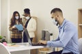 Man employee in face medical mask working on laptop in office after lockdown Royalty Free Stock Photo