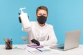 Man employee in hygienic face mask and gloves giving bottle with antiseptic gel, disinfection to prevent coronavirus Royalty Free Stock Photo