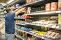 The man employer wear surgical mask arranging food at the supermarket aisle for prepare to shopper buy to hoarding food