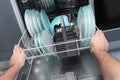 Man empty out the dishwasher in kitchen.Close-up of male hands loading dishes to the dishwasher