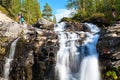 Man end woman hikers standing next to beautiful waterfall in the Khibiny mountains. The Kola peninsula, Russia