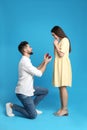 Man with engagement ring making marriage proposal to girlfriend on background