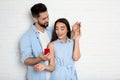 Man with engagement ring making marriage proposal to girlfriend near brick wall