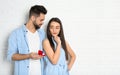 Man with engagement ring making marriage proposal to girlfriend near brick wall