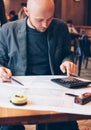 Man engineer designer architect reading drawings at table in cafe