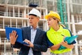 Man engineer standing on a construction site with a young woman worker monitors the construction plan on a laptop Royalty Free Stock Photo