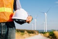 Engineer holding safety helmet stands at windmill field Royalty Free Stock Photo