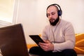 Man enjoying at his home office working with tablet and listening music using laptop Royalty Free Stock Photo