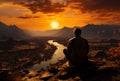 A man enjoying a peaceful sunset while sitting on a rock Royalty Free Stock Photo