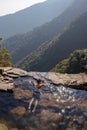 Man enjoying the pristine view at natural swimming pool at mountain cliff from top angles