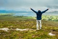 Man enjoying view on Clew Bay from Croagh Patrick, Westport, county Mayo, Ireland. Blue cloudy sky, Hand in the air Royalty Free Stock Photo